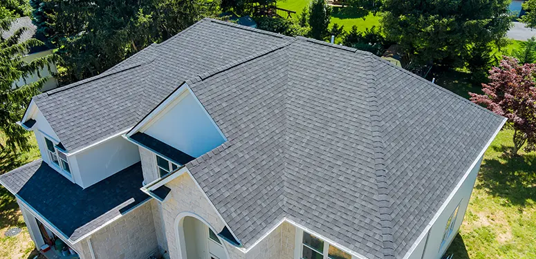 Aerial view of a gray shingled roof on a modern two-story house with green lawn nearby?